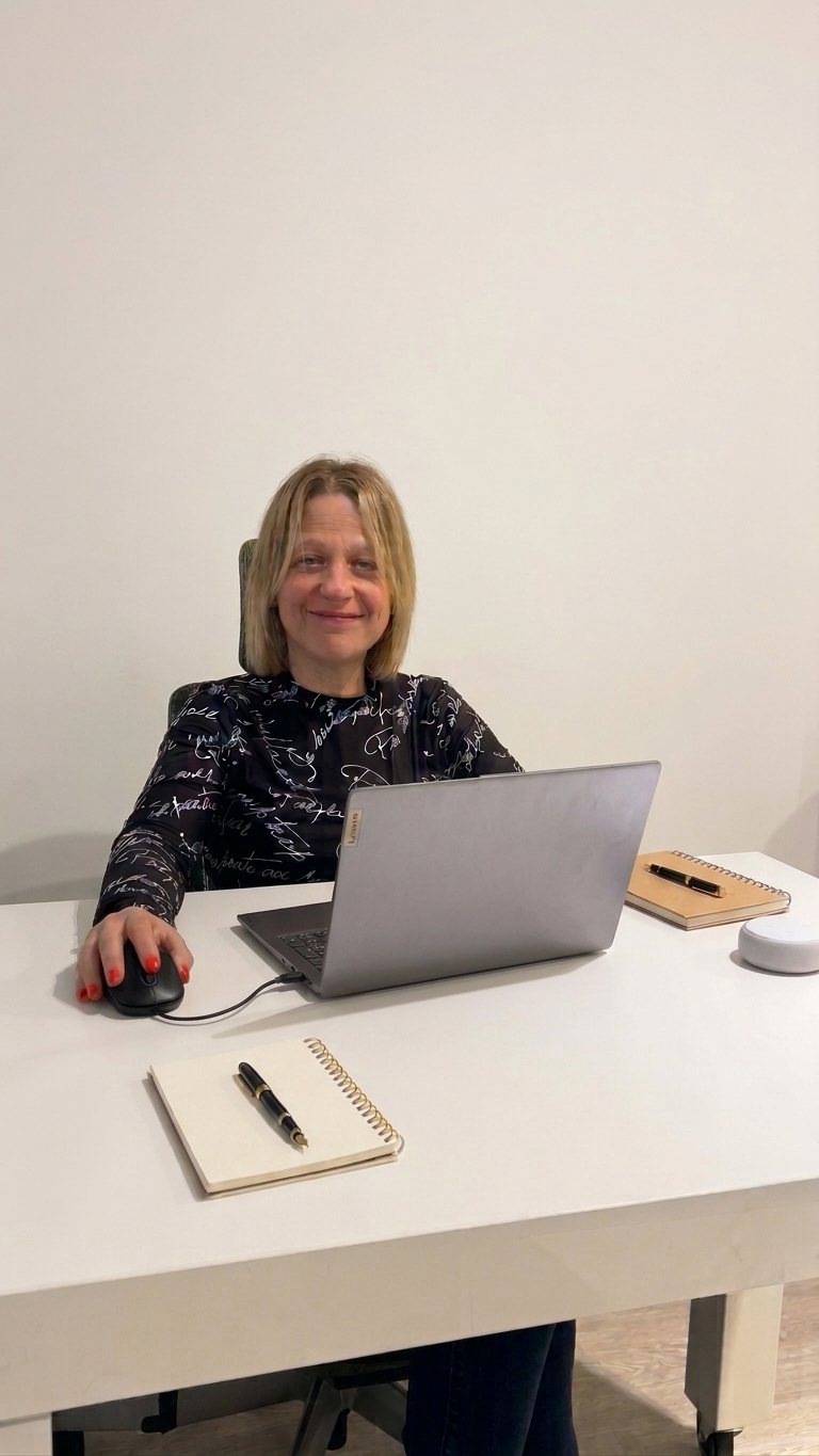 Lic. Laura Rabinovich sentada en su escritorio del consultorio, sonriendo junto a su notebook
